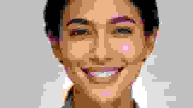 A professional headshot of a smiling woman with clear skin and bright eyes.