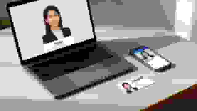 Professional headshots of a female agent displayed on a laptop, smartphone, and business card on a desk.